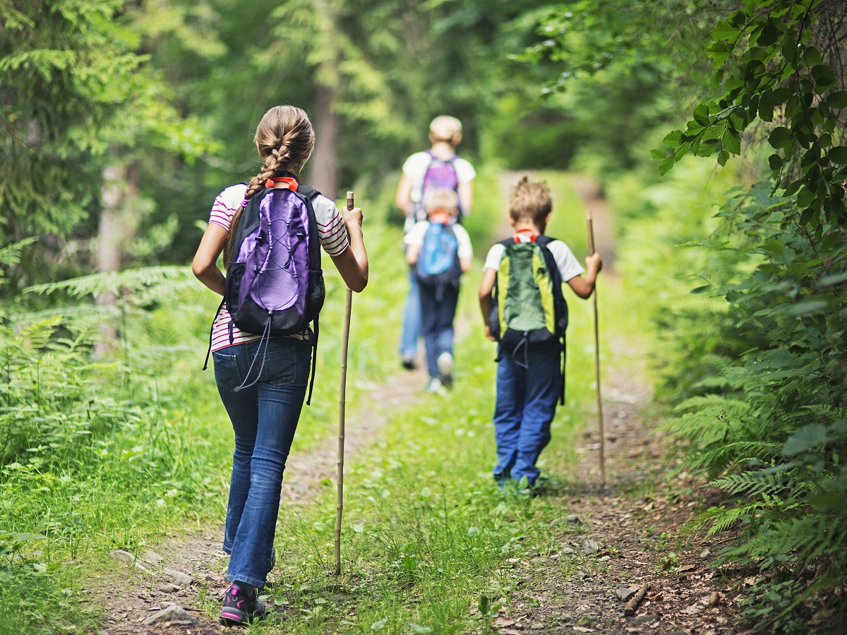 Family wearing backpacks hiking together outdoors