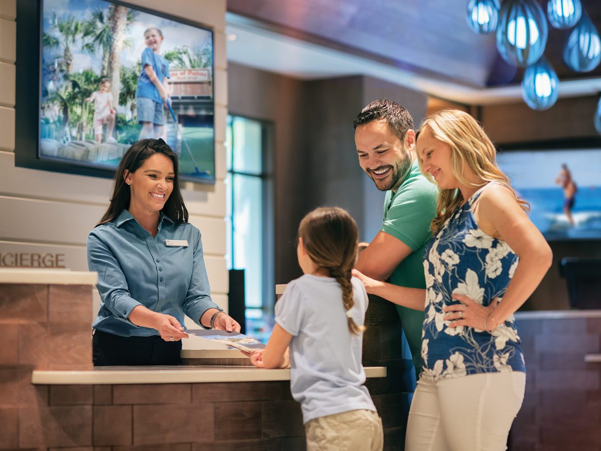 Friendly resort staff member helping happy family check in